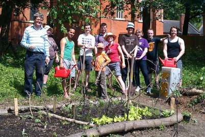 Growers in St Johns Garden with tools behind a bed of vegetables