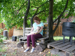 A volunteer sitting on a bench at the Edible Garden